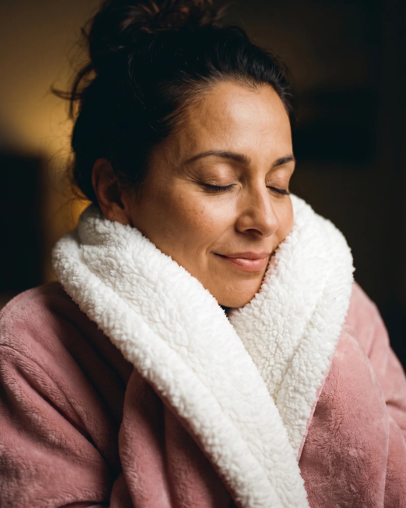 Woman with her eyes closed, chin tucked into the sherpa collar of her Hugwarm